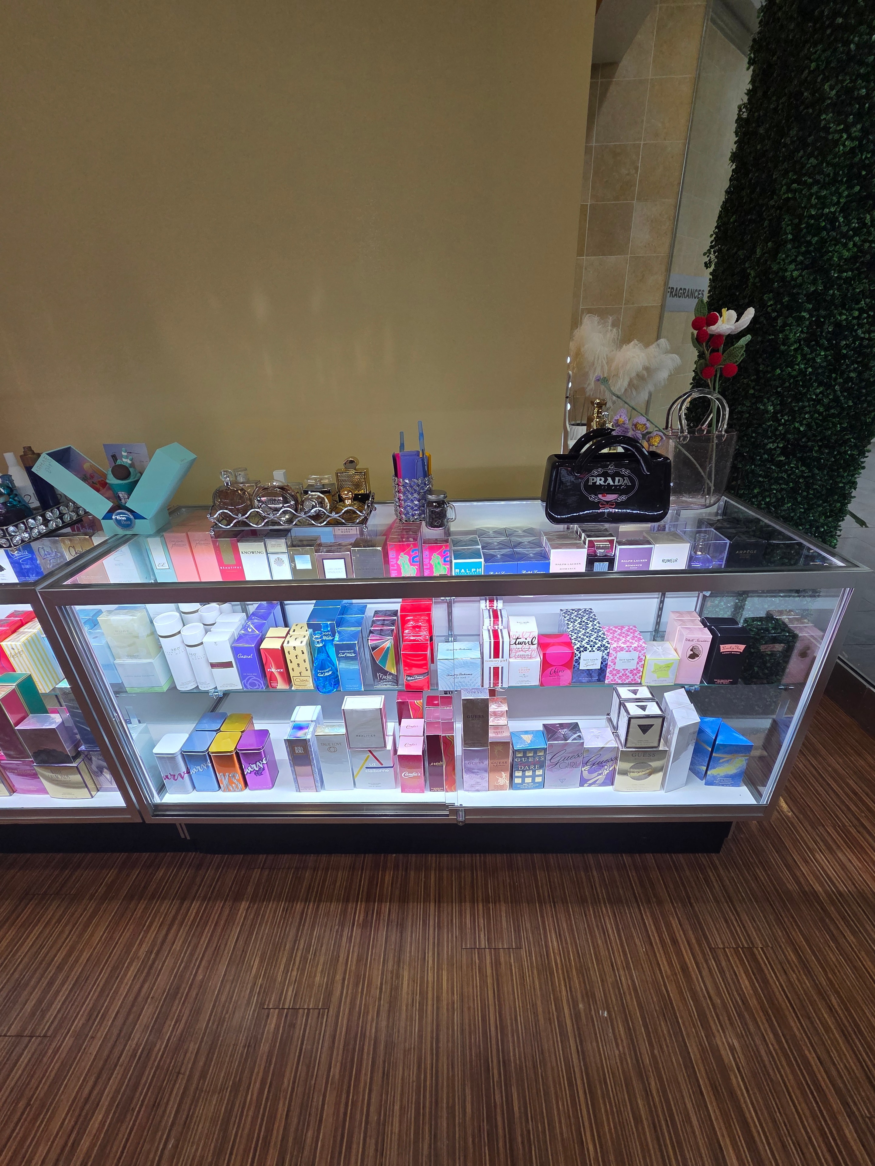 Illuminated glass display case filled with colorful fragrance boxes