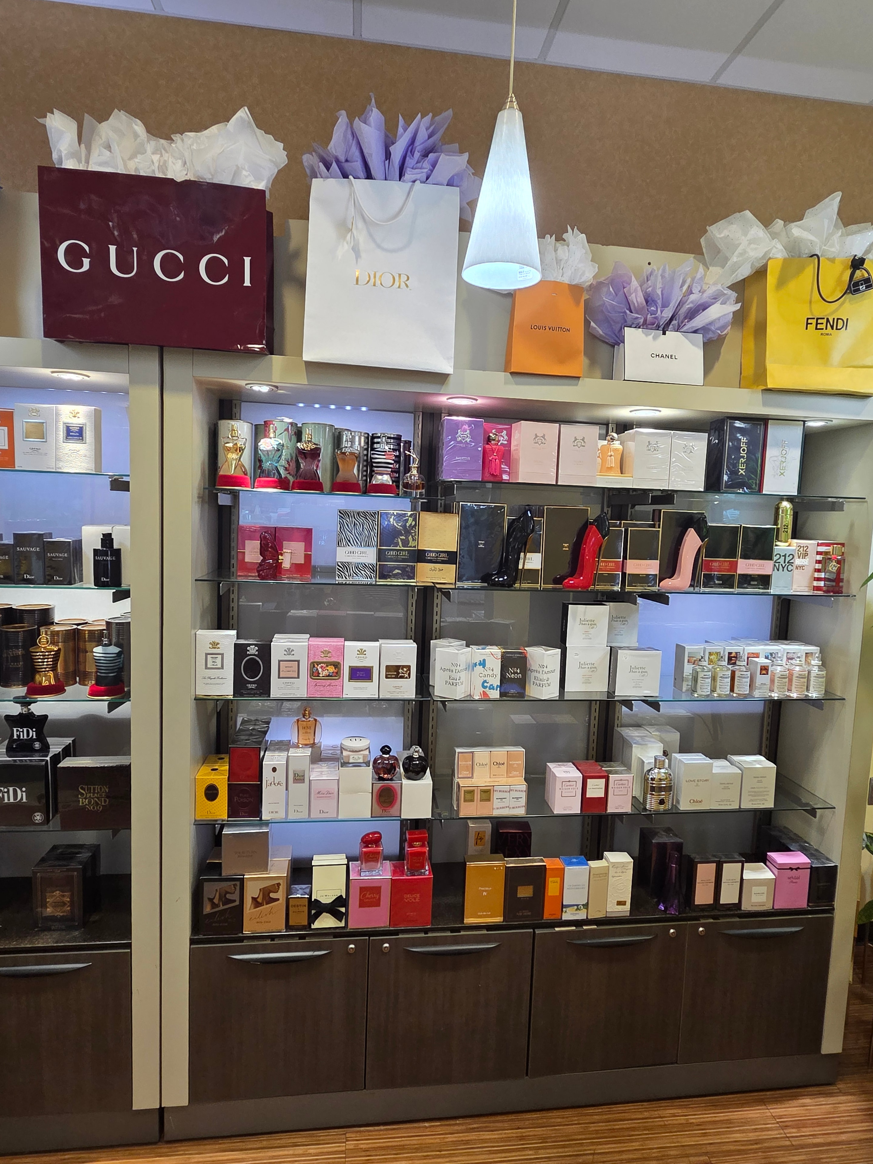 Display case with luxury brand shopping bags and fragrance collection